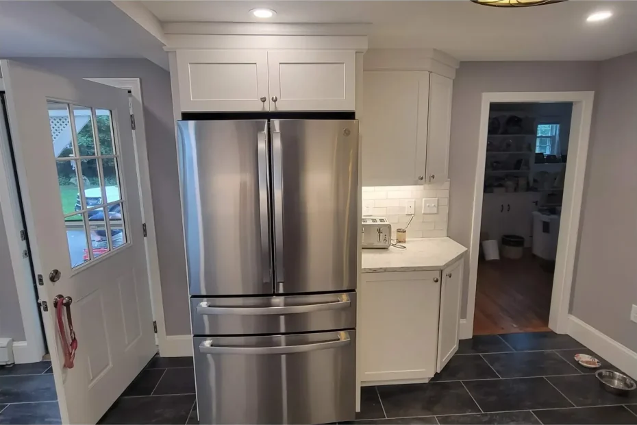 Kitchen with stainless refrigerator, white cabinets, subway-tile backsplash, stone counter and dark tile floor